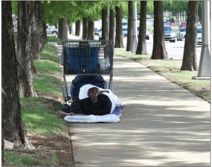 A man experiencing homelessness sleeps with his belongings nearby on June 10, alongside Lincoln Blvd in Oklahoma City. Heather Warlick/Oklahoma Watch