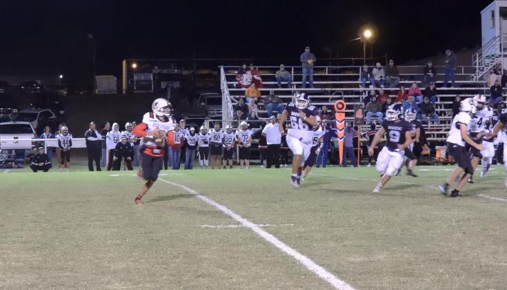 Rush Springs Redskin Jacob Caveness tries to run away from ECP Badgers Gunner Teakell and J.W. Barnes.