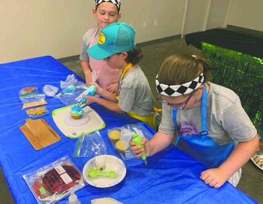 Parker Zamarron, Cade Selman and Alice Babcock, of Pauls Valley 4-H Club, work on their little guppies/gone fishing themed cupcakes during the Cupcake Wars competition at the Garvin County Fair Aug. 23. Courtesy photo