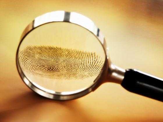 Stock image of fingerprint under magnifying glass.