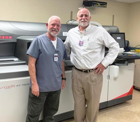 Matt Howsley, laboratory manager for Southern Plains Medical Center of Garvin County, and CEO Richard Mathis pose with the facility’s Ortho Vitros XT 7600 Integrated System Clinical Chemistry Analyzer. The analyzer is just one of the tools SPMC is using to bring a broader range of in-house services to the local community. Photo by Suzanne Mackey