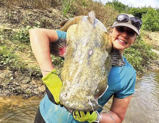 Pauls Valley‘s Jennifer Samford poses with one of the large flathead catfish she helped pull out of an Oklahoma creek during her first-ever noodling trip earlier this week. Courtesy photo