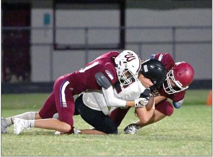 Wynnewood’s Phoenix Sparks and a fellow teammate tackle the Tishomingo ball carrier in Tuesday night’s victory over Tish, 14-6. News Star photo by Don Coffey