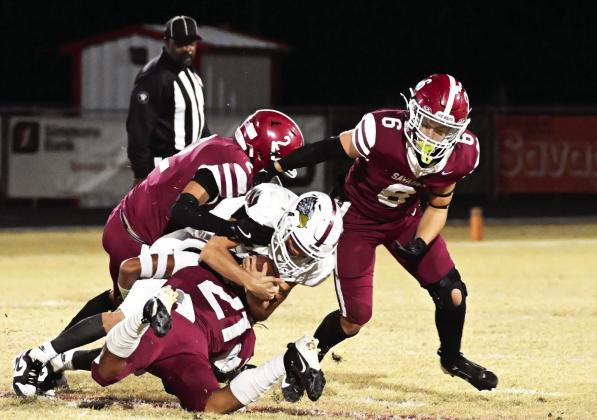 Wynnewood’s #2 Jett Anderson, #21 Brylan Williams and #6 Braylon Pierce gang-tackle the Sayer runningback for a loss in Friday night’s first round playoff win over Sayer. News Star photo by Don Coffey
