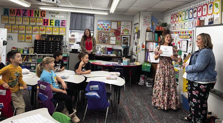 PVFAE’s Camille Milligan shares with Whitebead teacher Erica Shippey (far right) and her first-grade students that all three of the grant applications Shippey submitted were funded. News Star photo by Suzanne Mackey