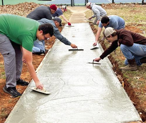Scouts from Pauls Valley’s Troop 73 work on smoothing the surface of a new section of sidewalk near the east side tennis courts at Wacker Park on Monday. News Star photo by Suzanne Mackey