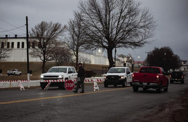 On days when the state executes an inmate, barricades block access to the Oklahoma State Penitentiary in McAlester. A guard is seen walking near one of the barricades a few hours before the state executed Gilbert Postelle on Feb. 17, 2022. Whitney Bryen/Oklahoma Watch