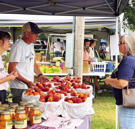 Peach vendors visit with shoppers at the 2024 Stratford Peach Festival.