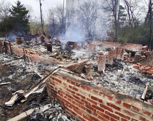 Remains of a house in the 1000 block of S. Chickasaw Street that burned Sunday night continued to smolder late Monday afternoon. Photo by Dexter Bernard.