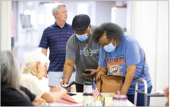 A voter presents their identification to a precinct official at The Village Bible Church in The Village on June 16, 2026. Brent Fuchs/Oklahoma Watch