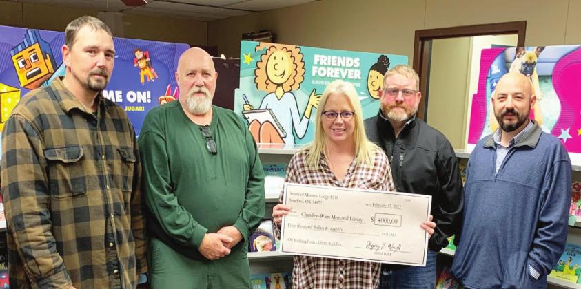Chase Lutrell, Jeffery Stringer, Jeffrey Wright, and John-Paul Townsend of Stratford Masonic Lodge #118 present librarian, Teresia Jors (center), with a $4,000 check in support of library programming. Courtesy photo