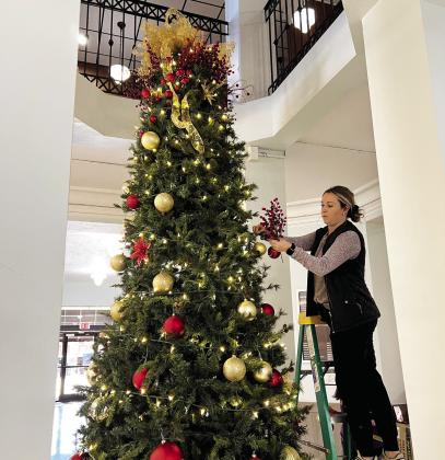 County employee Marissa Arnold helps decorate the first floor Christmas tree at the Garvin County Courthouse Nov. 22. News Star photo by Suzanne Mackey