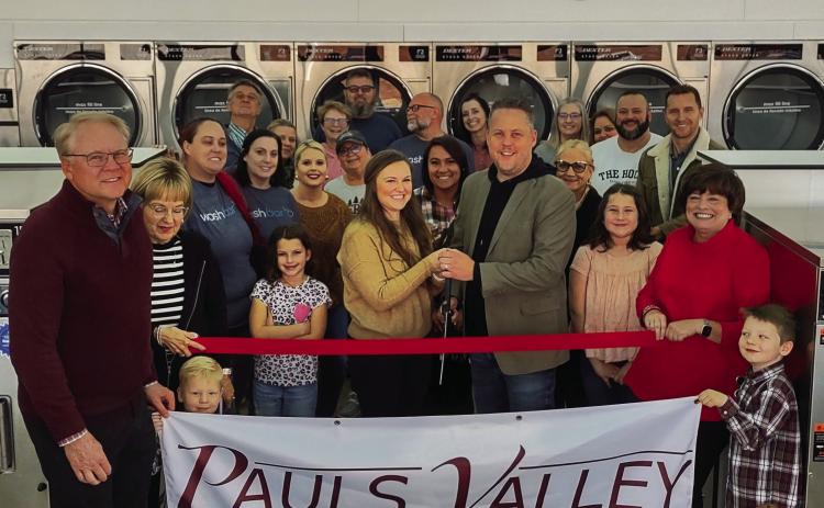 Josh and Hannah Chapman (front row, center), owners of the Washbar, were welcomed as new Pauls Valley Chamber of Commerce members with a ribbon cutting celebration Tuesday. The laundromat offers coin/card self serve, as well as full-service wash and fold laundry drop-off and press and starch service for both commercial and residential customers. The Washbar, at 500 S. Chickasaw St., is open from 8 a.m. to 9 p.m. seven days a week. Courtesy photo