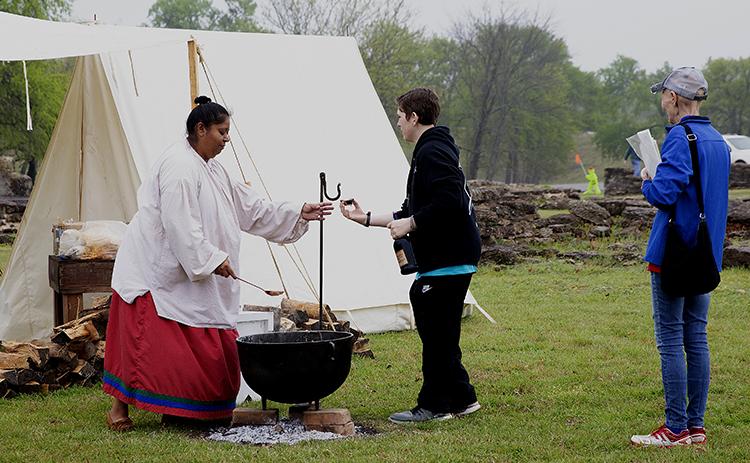 A First American woman shares a sample of pashofa — a traditional Chickasaw dish — to visitors during the 2019 Fur Trade Era Rendezvous at Fort Washita. The 2023 Rendezvous will show participants what life was like in early American history. Courtesy photo.