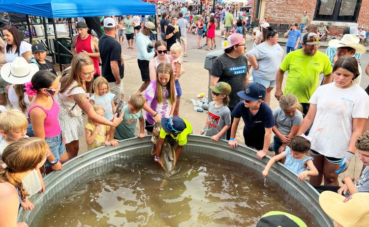 Spectators getting a closer look at some of the big catfish on display at the 2025 Okie Noodling Tournament. News Star photo by Suzanne Mackey