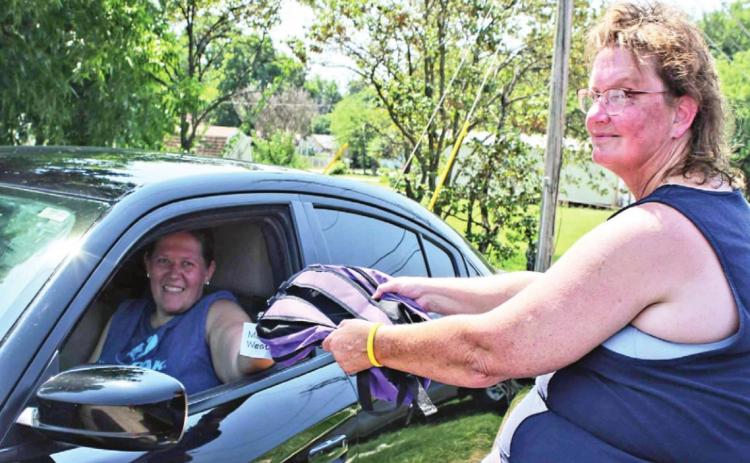 Bev Barker hands out a free backpack at the Linday Senior Center over the weekend. Volunteers distributed 500 backpacks to area students in need. Photo by Ashley Gallagher
