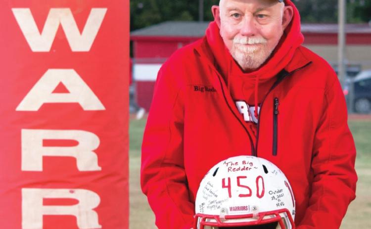 Maysville's Roger Perrin poses with a signed helmet the Maysville Warrior football team presented him to mark his 450th consecutive Maysville game earlier this season. His hat, emblazoned with 450 to commemorate the accomplishment, was custom-made for him by Tamara Tadlock of Elmore City.