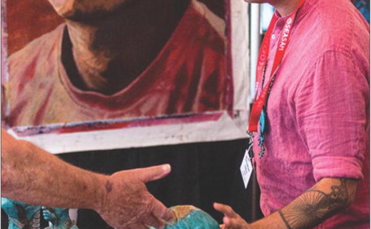 National and internationally acclaimed Chickasaw artist Addison Karl visits with a patron during the 2022 Southeastern Arts Show and Market (SEASAM). SEASAM is set to begin Oct. 6 during the Chickasaw Annual Meeting and Festival.