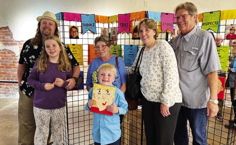 Owen Luker (center) poses with his self-portrait and his family during the “Characteristics on Canvas” art show at The Vault in downtown Pauls Valley Tuesday evening. The show featured self-portraits by students in Erica Shippey’s first grade class at Whitebead School. Each piece included a statement from the artist describing a skill, ability or personality trait that makes them uniquely them. The project was made possible by a grant from the Pauls Valley Foundation for Academic Excellence.