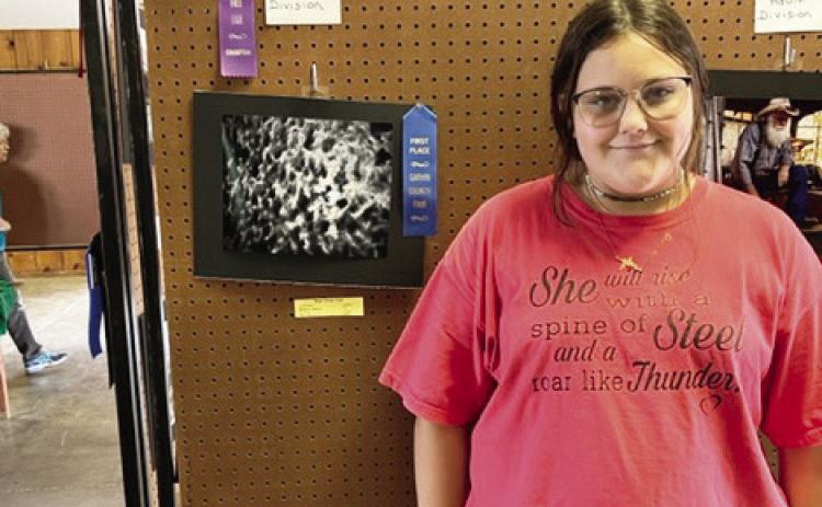 Ellexys Madison of Maysville poses with her photo entry at the Garvin County Free Fair last week. Madison won first place and Best of Show in the youth division.