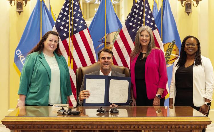 (L-R) Health Minds Policy Initiative Policy Director Brittany Hayes, Rep. Cynthia Roe, and Behavioral Health Workforce Project Director Tequia Sier join Gov. Kevin Stitt (seated) for the ceremonial signing of House Bill 3330 on Tuesday, July 9 at the Oklahoma State Capitol. Courtesy photo