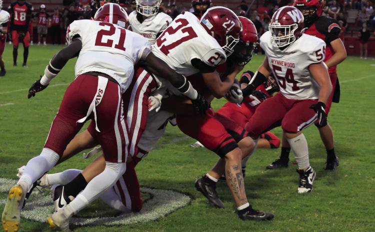 Wynnewood’s Desmond Brown (#21), Jaxson Bourland (#27), Trae Williams and Peyton Henderson (#54) tackle the Frederick runningback for a short gain in the Savages 62-8 win. By Mike Arie Photo by Don Coffey